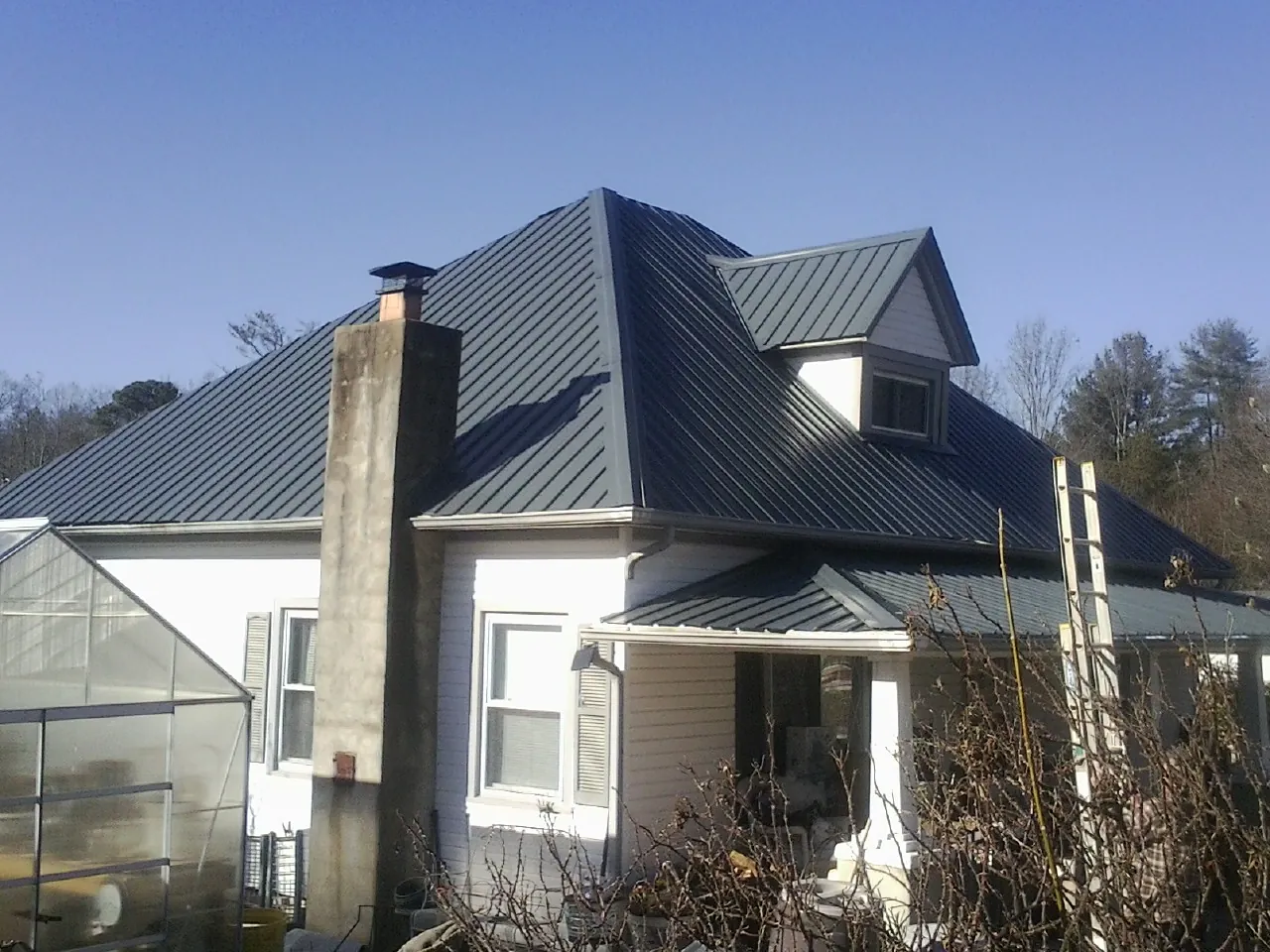 Dark blue standing seam metal roof on a white farmhouse with dormer — Slate & Tile Roof Repair by Roofing Brothers in Port Republic
