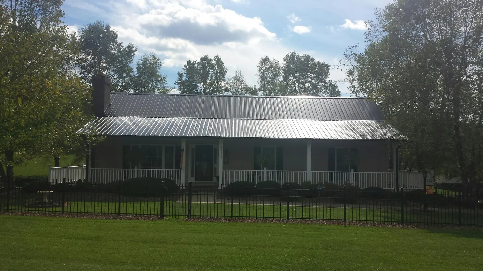 Gray metal roof on a brick ranch with a full width front porch — Gutter Guard Installation work by our crew in Port Republic