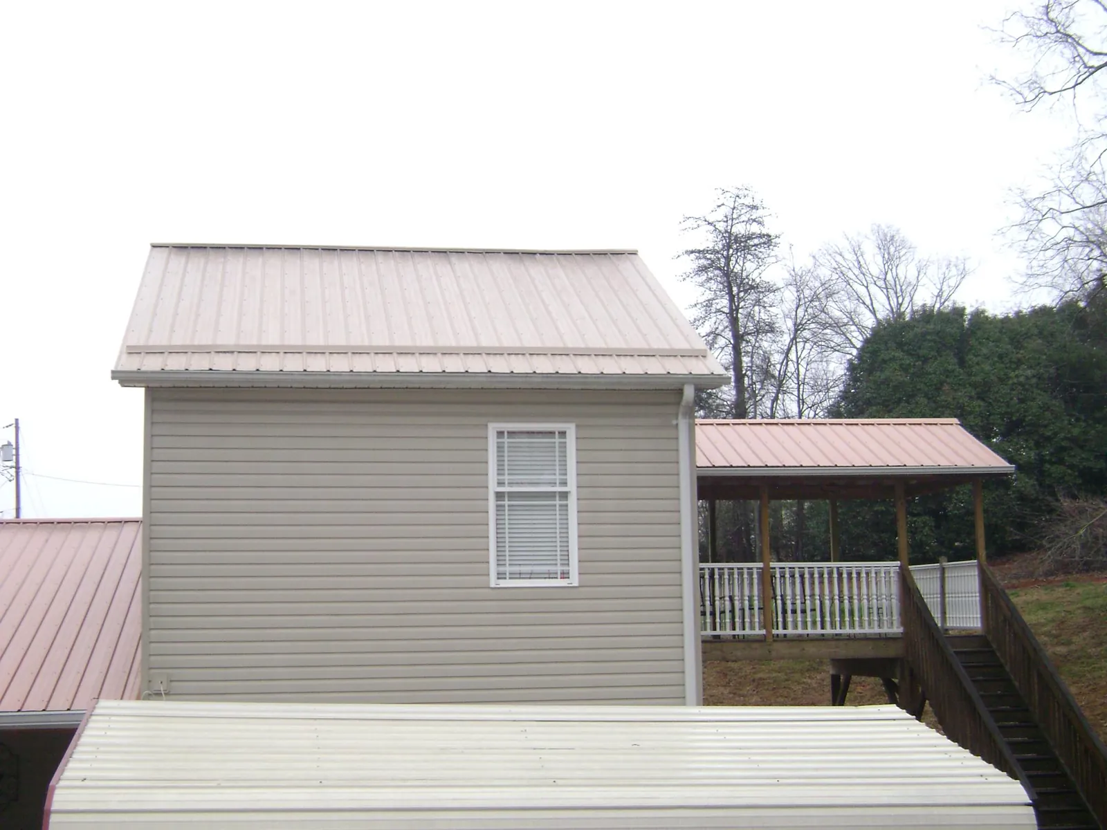 Tan metal roofs on a two story addition and attached porch, from a Roof Replacement job in Port Republic